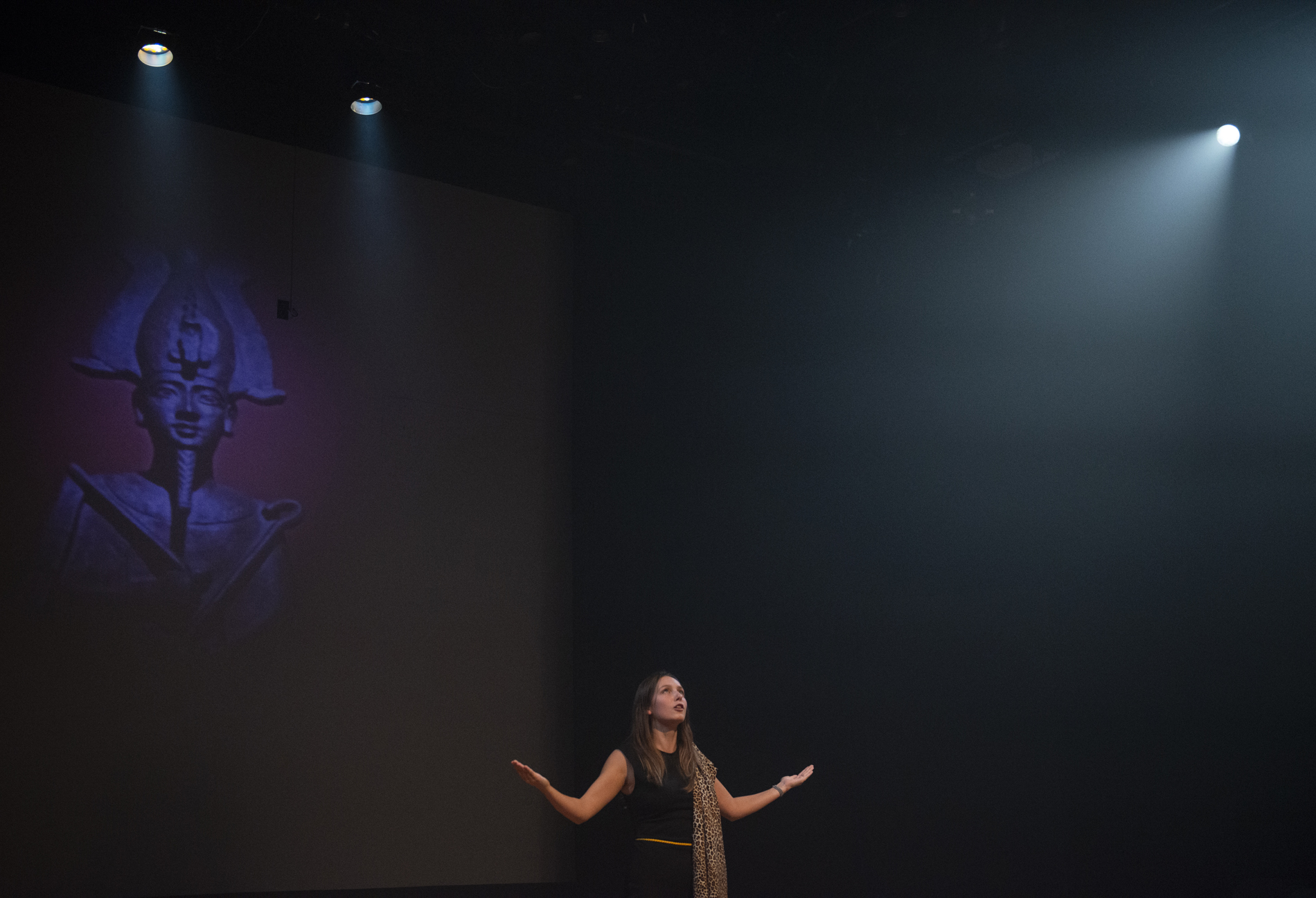 A performer with her arms out in front of an image of Isis